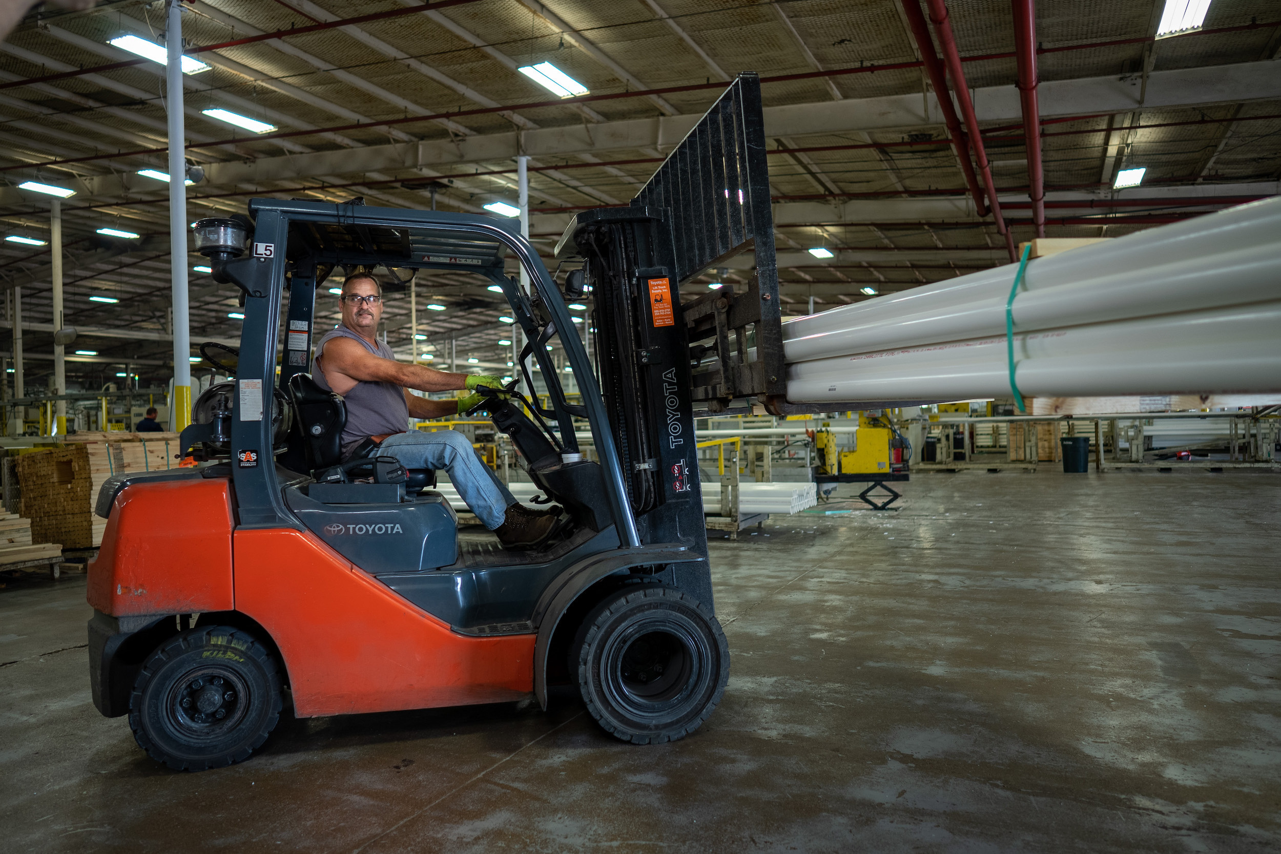 Employee on a forklift carrying some pipe
